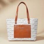 white and brown tote bag with a repeating logo pattern and an exterior pocket.