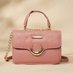 small, pink, faux leather top-handle and crossbody bag with a gold-tone chain strap and crescent moon detail.