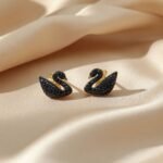 Swarovski Iconic Swan Stud Earrings in black, featuring a rose gold-tone plated finish and adorned with black crystals.