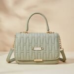 women's quilted top handle crossbody bag in a light green or sage color.
