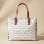 white and brown tote bag with a repeating logo pattern and brown leather-look handles.