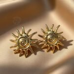earrings are the Solar Essence Studs, a gold-plated,
