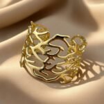 gold-tone cuff bracelet featuring an intricate